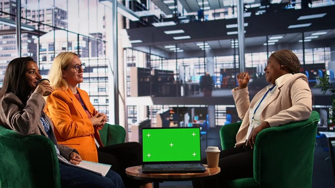 Женщины разных этнических групп обсуждают новые стратегии рядом с зеленым экраном.